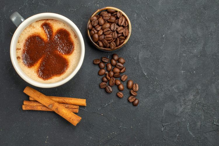 top view a cup of coffee bowl with coffee seeds cinnamon sticks on dark isolated background free place